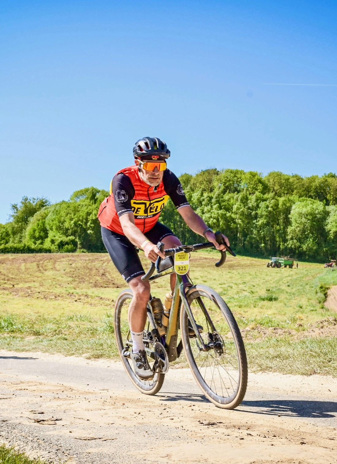 Cyclist racing on a dirt road with trees in background