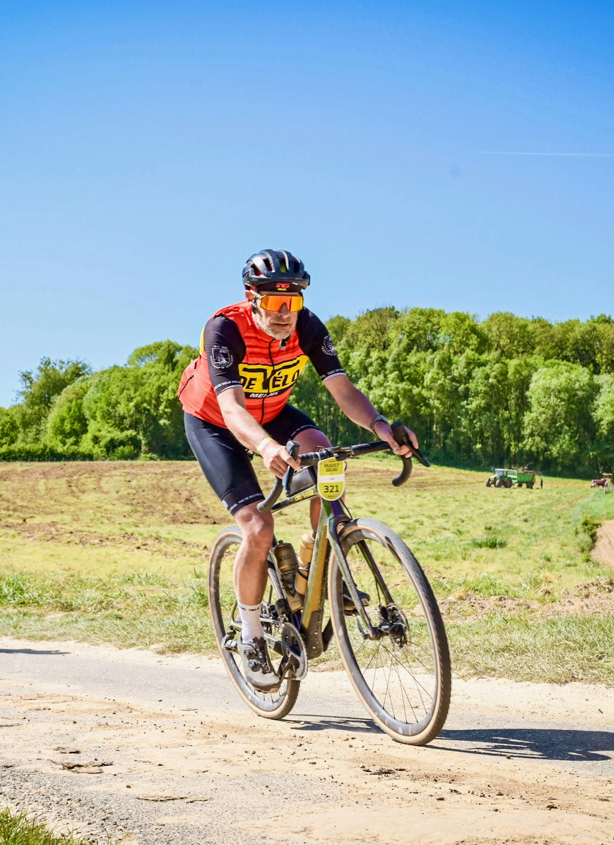 Cyclist racing on a dirt road with trees in background